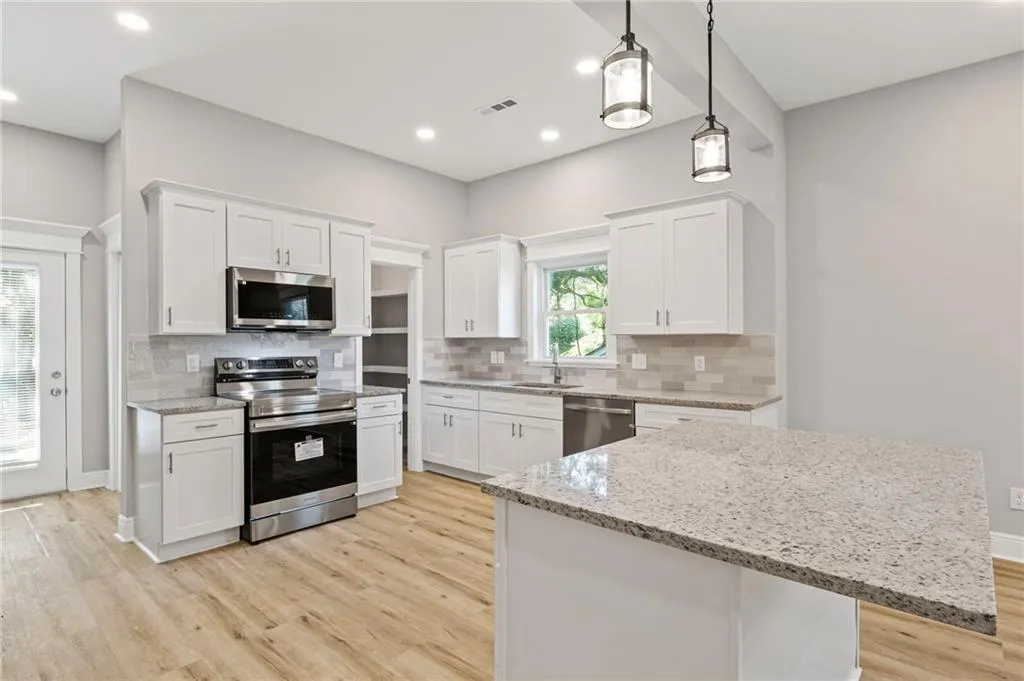 Kitchen featuring stainless steel appliances, light wood-style floors, white cabinets, and recessed lighting