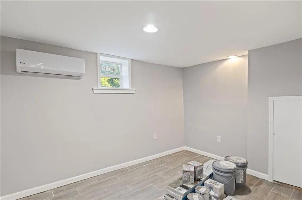 Basement with a wall mounted AC, wood finish floors, and recessed lighting