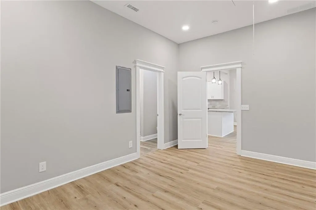 Unfurnished room with electric panel, light wood-style floors, attic access, and recessed lighting
