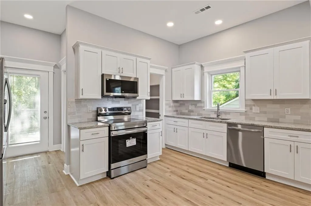 Kitchen with stainless steel appliances, white cabinetry, light wood-type flooring, tasteful backsplash, and recessed lighting