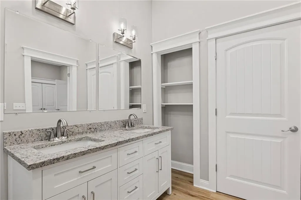 Full bath featuring double vanity, wood finished floors, and a closet