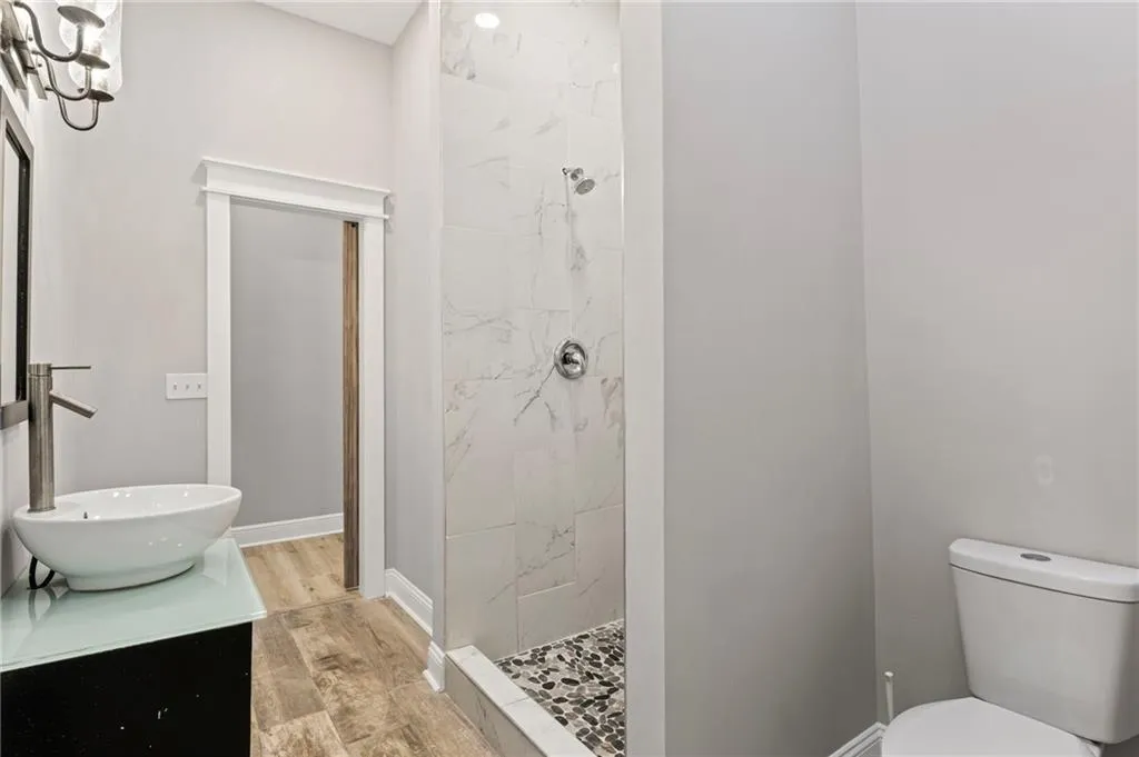 Full bath with vanity, wood finished floors, and tiled shower