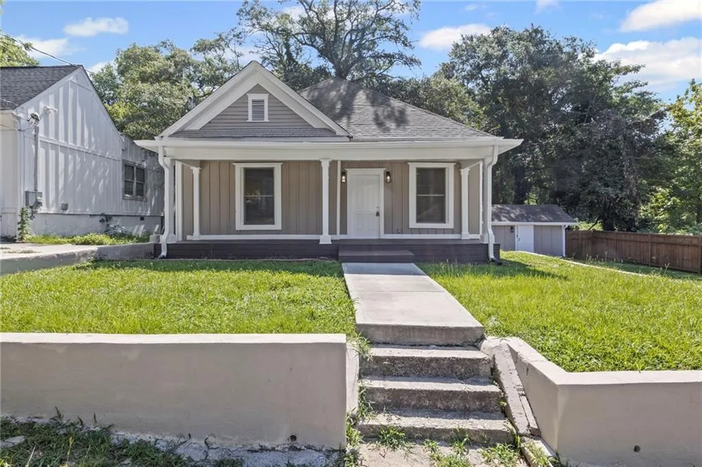 View of front of house with a porch, board and batten siding, a shingled roof, and an outdoor structure