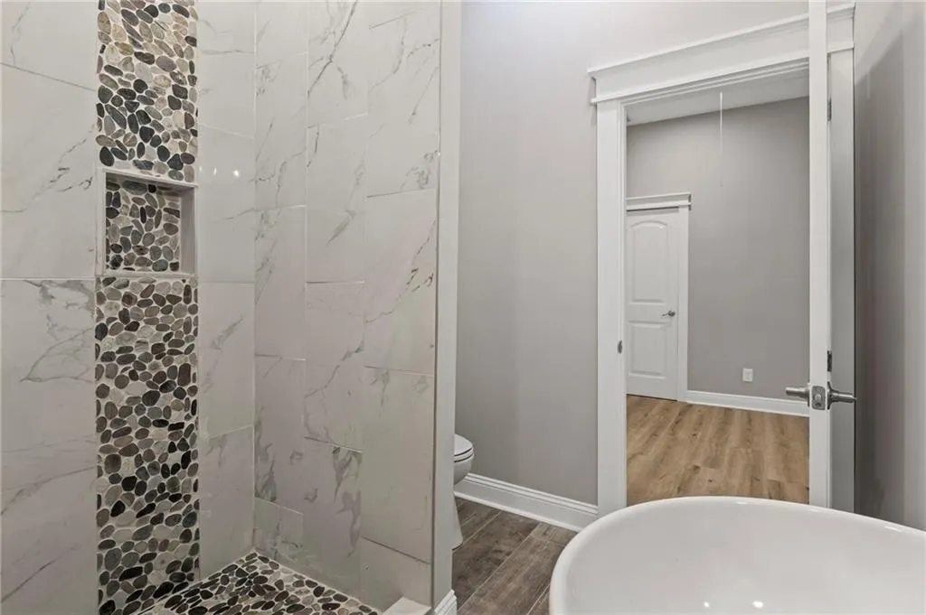 Bathroom with wood finished floors and a tile shower