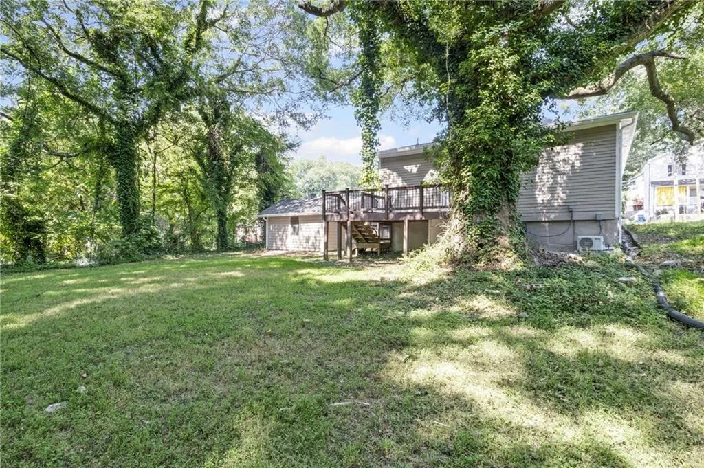 View of green lawn featuring stairs and a wooden deck