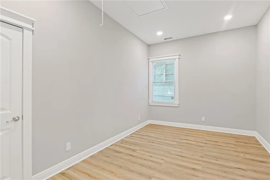 Empty room with light wood-style flooring, recessed lighting, and attic access
