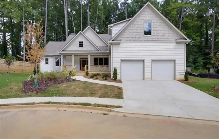 Craftsman-style exterior with white siding and gray shake accents, a covered front porch with wood railings, a concrete driveway, and a two-car garage