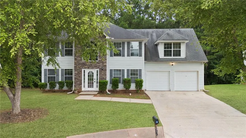 Two-story residence featuring a stone and siding facade, a two-car garage, and a concrete driveway
