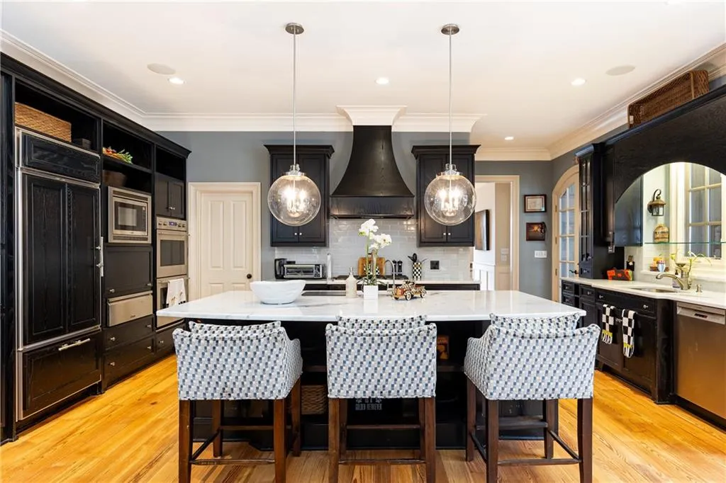 Gourmet Kitchen with heart of pine floor, stained wood cabinetry, including large breakfast-bar island, quartzite counter tops, glass tile backsplash and fine high-end appliances.