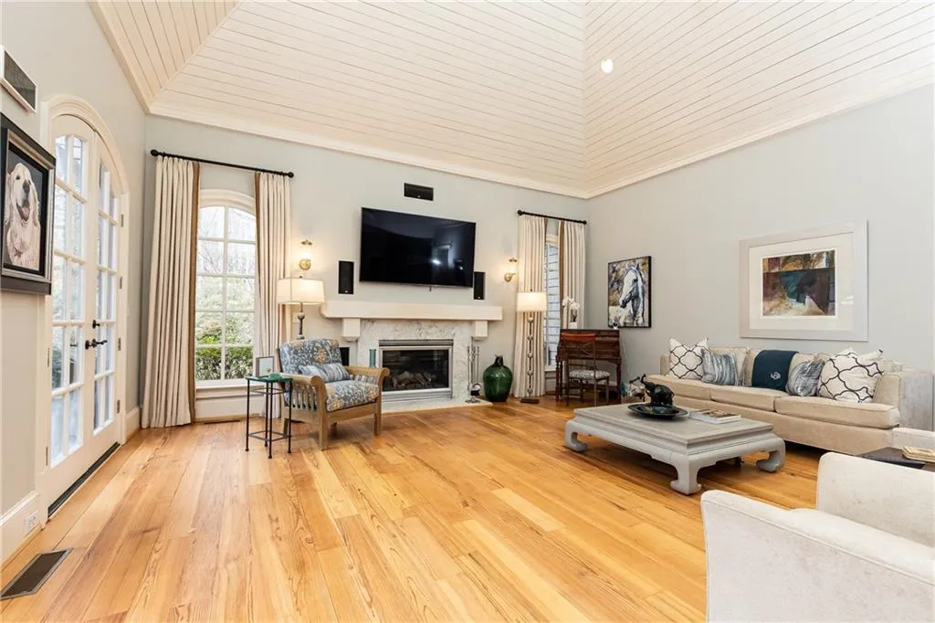 Vaulted-Ceiling Family Room open from Kitchen, has a gas-log fireplace. There are 3 sets of arched French doors opening to the patio and backyard.