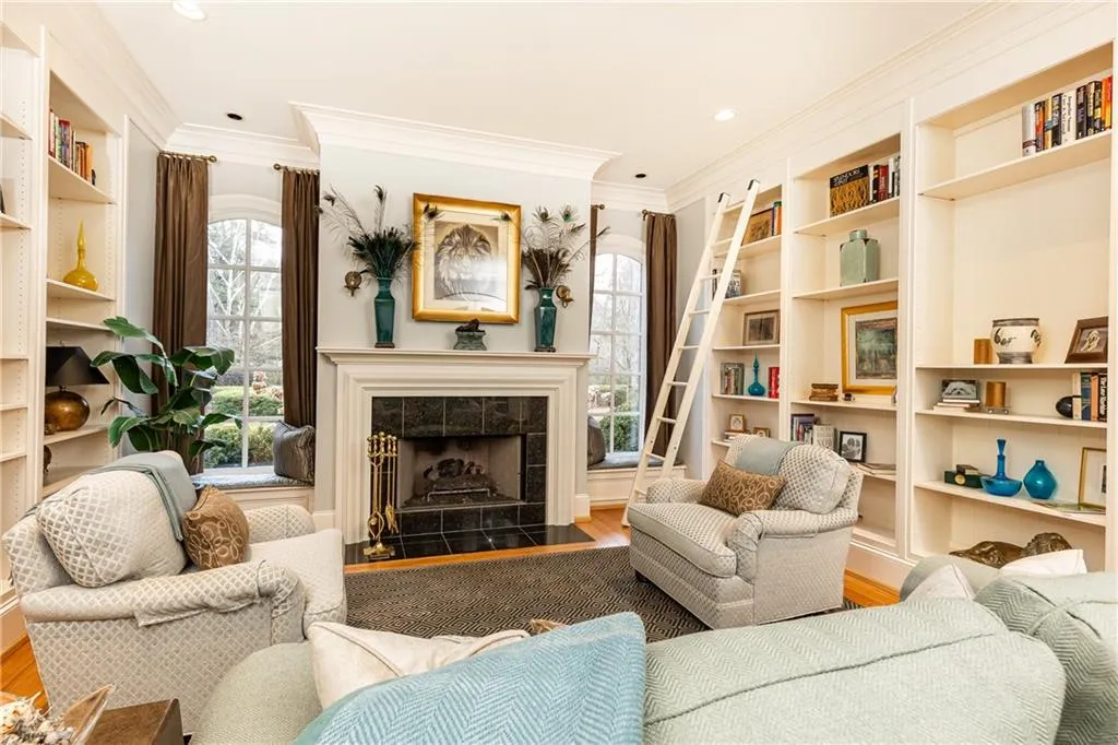 Living Room/Study. Note window seats on either side of fireplace and rolling ladder to reach top shelves.