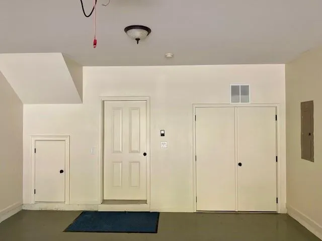 Garage with baseboards and electric panel