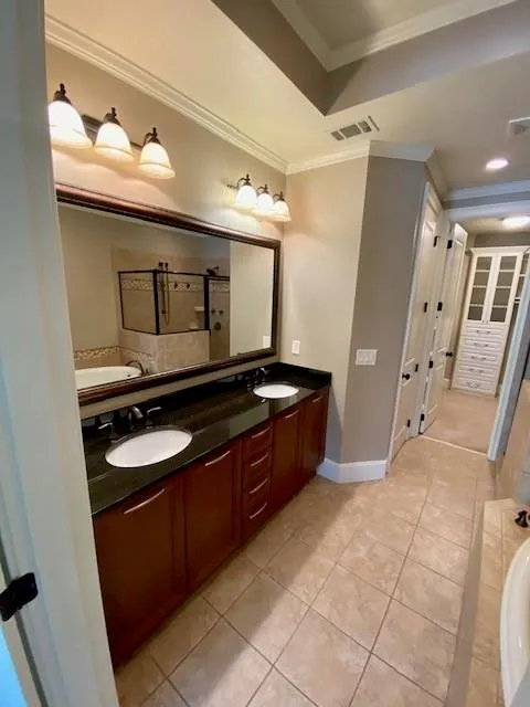 Full bath with ornamental molding, light tile patterned floors, double vanity, and a garden tub