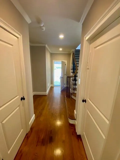 Hallway featuring ornamental molding, stairway, and dark wood-style floors