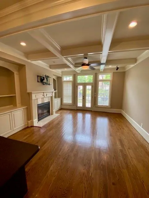 Unfurnished living room with coffered ceiling, beamed ceiling, a premium fireplace, dark wood-style flooring, and recessed lighting
