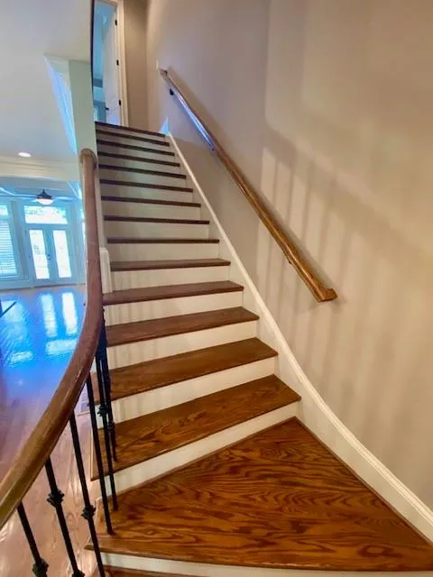 Stairway with wood finished floors and crown molding