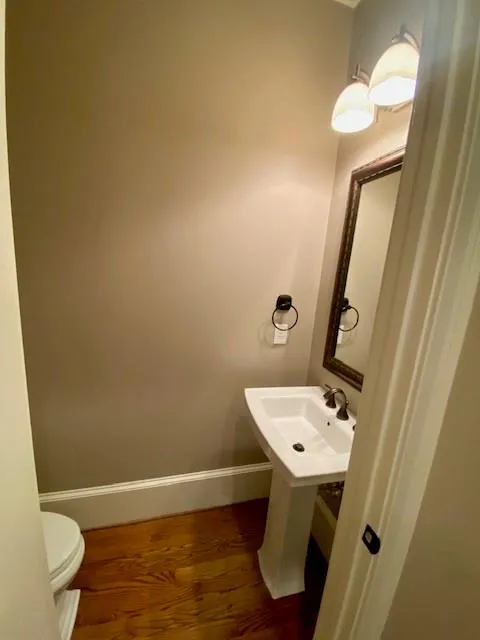 Half bath featuring dark wood-style floors and baseboards