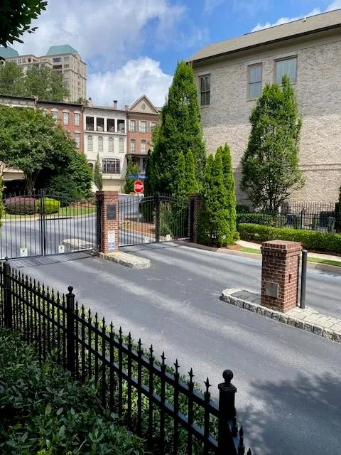 View of asphalt road featuring traffic signs, curbs, a gated entry, and a gate