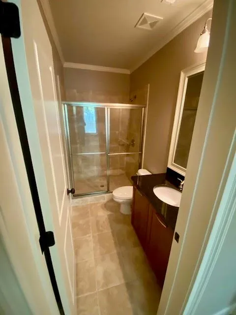 Bathroom with vanity, a shower stall, crown molding, and light tile patterned floors