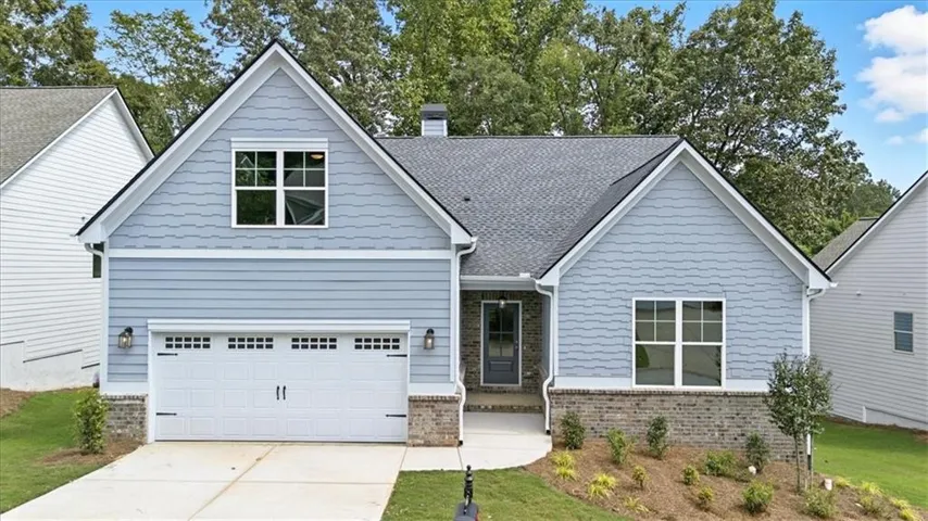 Gable roof home featuring light blue horizontal and shingle siding with a brick facade