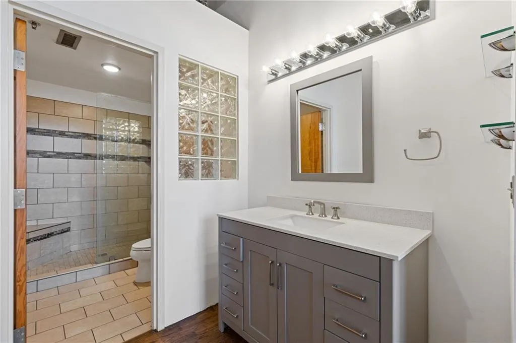Full bath with vanity, a shower stall, and dark wood-type flooring