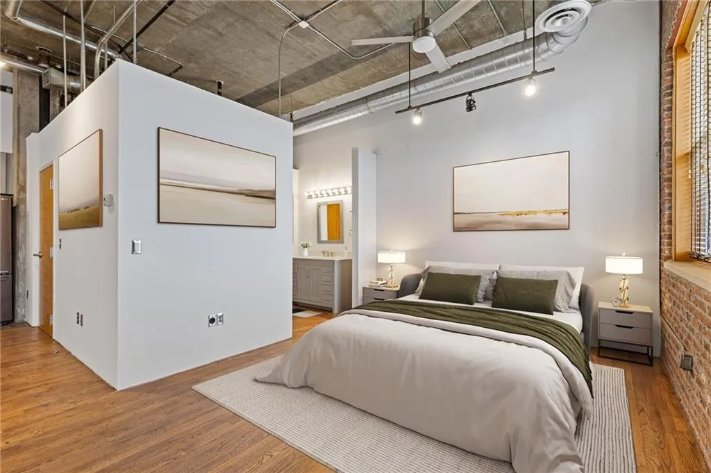 Bedroom with light wood-style floors, connected bathroom, and a ceiling fan