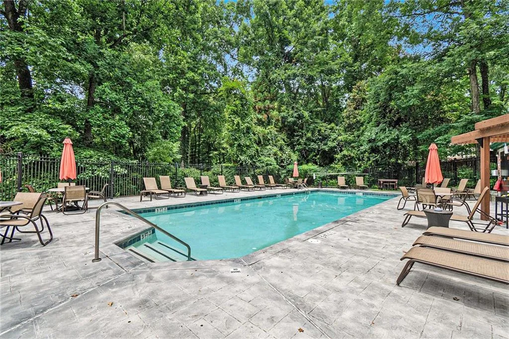 Community pool featuring a patio area and view of wooded area