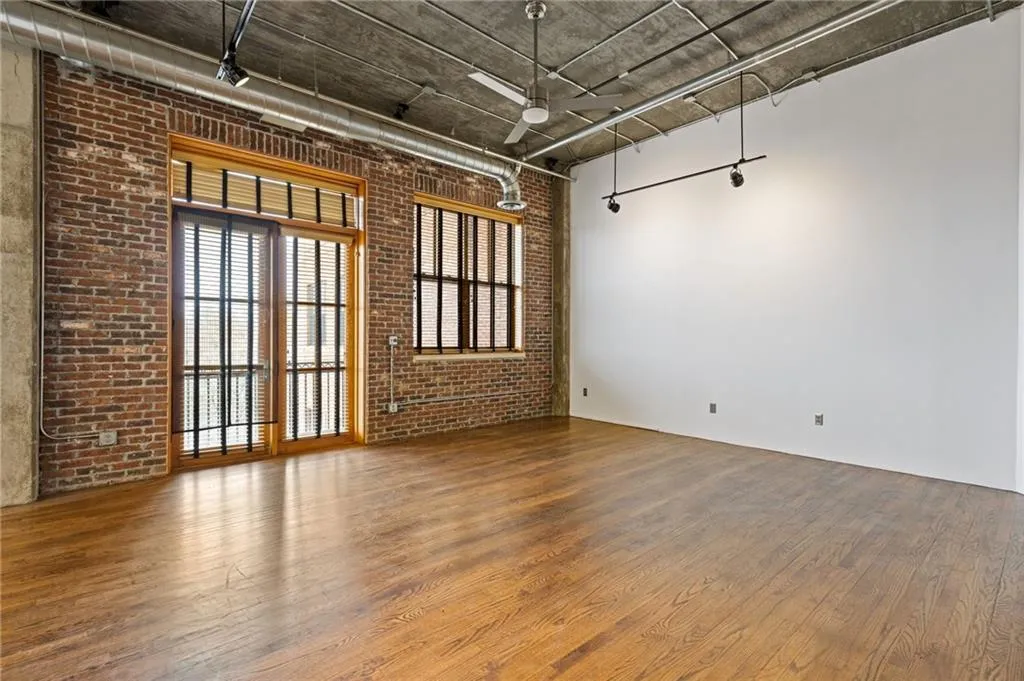 Spare room featuring a high concrete ceiling, brick wall, dark wood-type flooring, and plenty of natural light