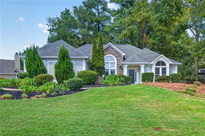 Stone facade accents, arched window designs, covered entry, and established landscaping