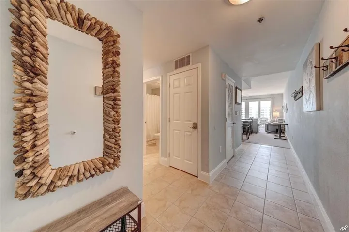 Corridor featuring baseboards, visible vents, and light tile patterned floors