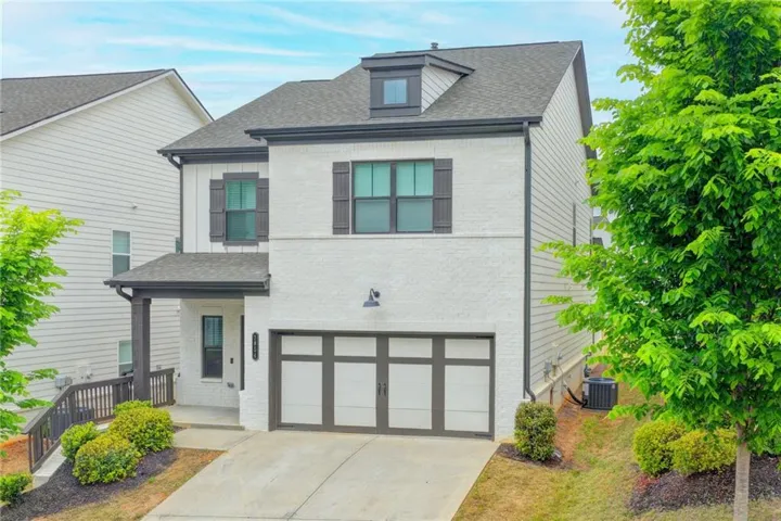 Two-story home featuring a white brick and siding exterior, dark trim, a two-car garage, and a covered porch