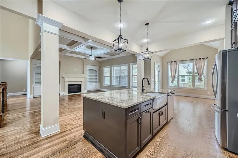 Kitchen with dark brown cabinetry, open floor plan, coffered ceiling, appliances with stainless steel finishes, and beam ceiling