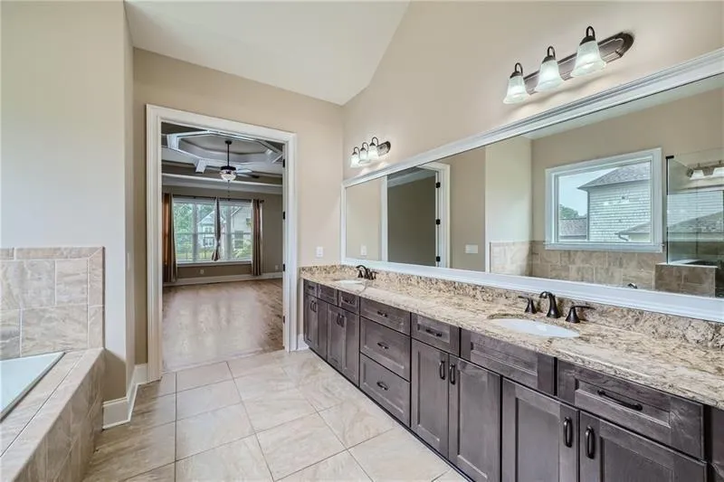 Full bathroom featuring coffered ceiling, a garden tub, beam ceiling, tiled shower, and light tile patterned floors