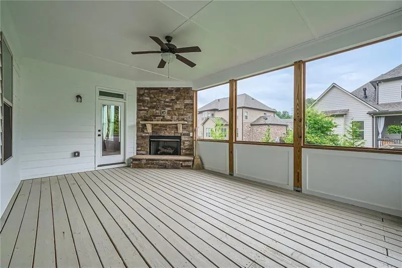 Unfurnished sunroom featuring ceiling fan, healthy amount of natural light, and a stone fireplace