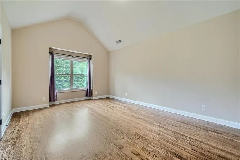 Empty room featuring light wood-style floors and high vaulted ceiling