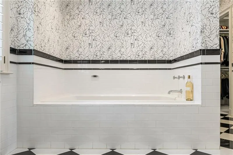 Bathroom with a walk in closet, a bath, and tile walls