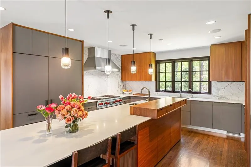 Kitchen with wall chimney range hood, modern cabinets, light countertops, a sink, and dark wood-type flooring