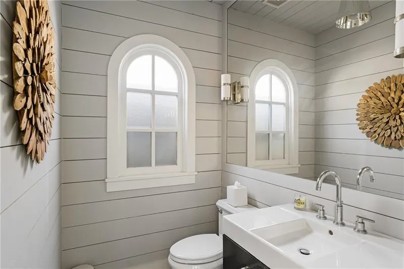 Bathroom featuring a sink, wood walls, toilet, and plenty of natural light