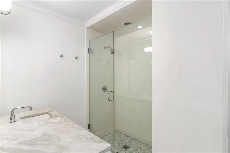 Full bathroom featuring a sink, ornamental molding, and a shower stall