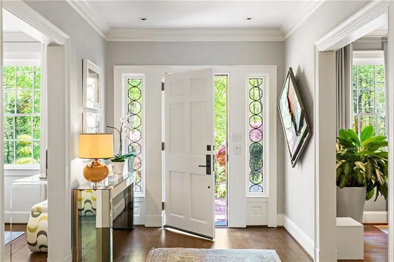 Foyer with healthy amount of natural light, wood finished floors, crown molding, and baseboards