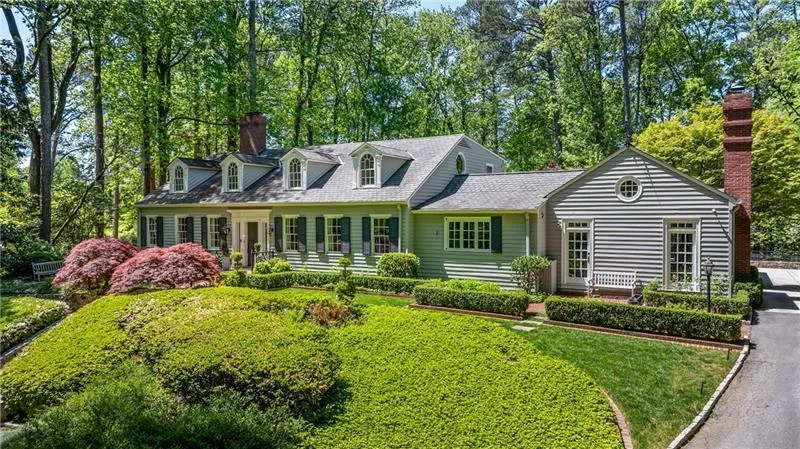 New england style home with a chimney and a front yard
