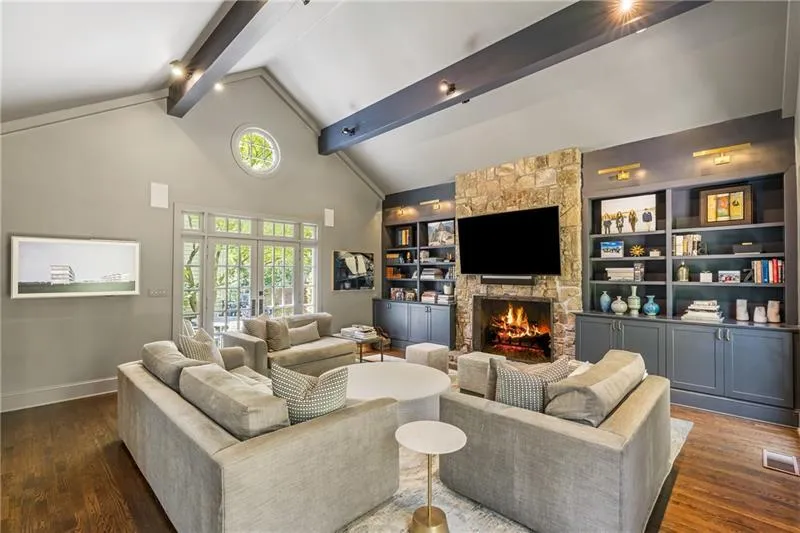 Living area featuring beamed ceiling, a fireplace, dark wood-type flooring, baseboards, and high vaulted ceiling