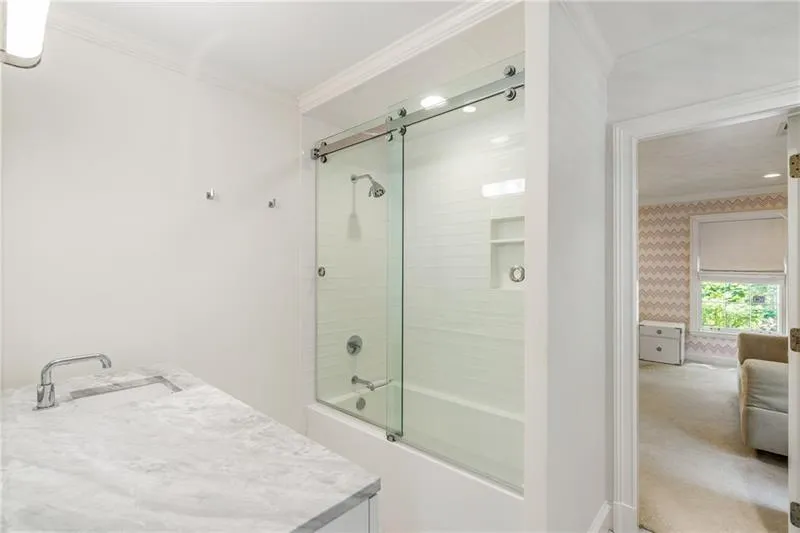 Bathroom with a sink, crown molding, combined bath / shower with glass door, and wallpapered walls