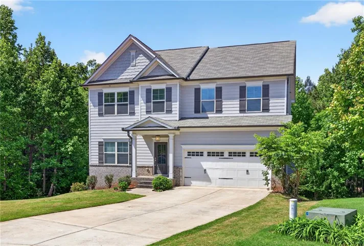 Two-story residence featuring light gray siding with stone-look accents, a covered front entry, and a two-car garage