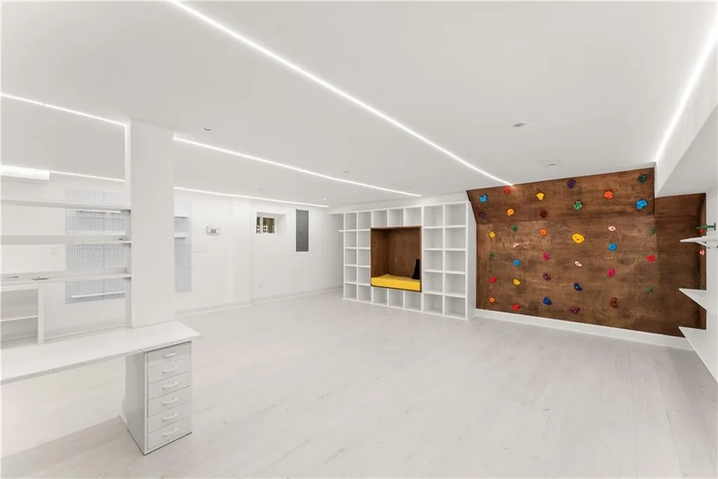 Finished basement featuring light wood finished floors, built in shelves, and electric panel
