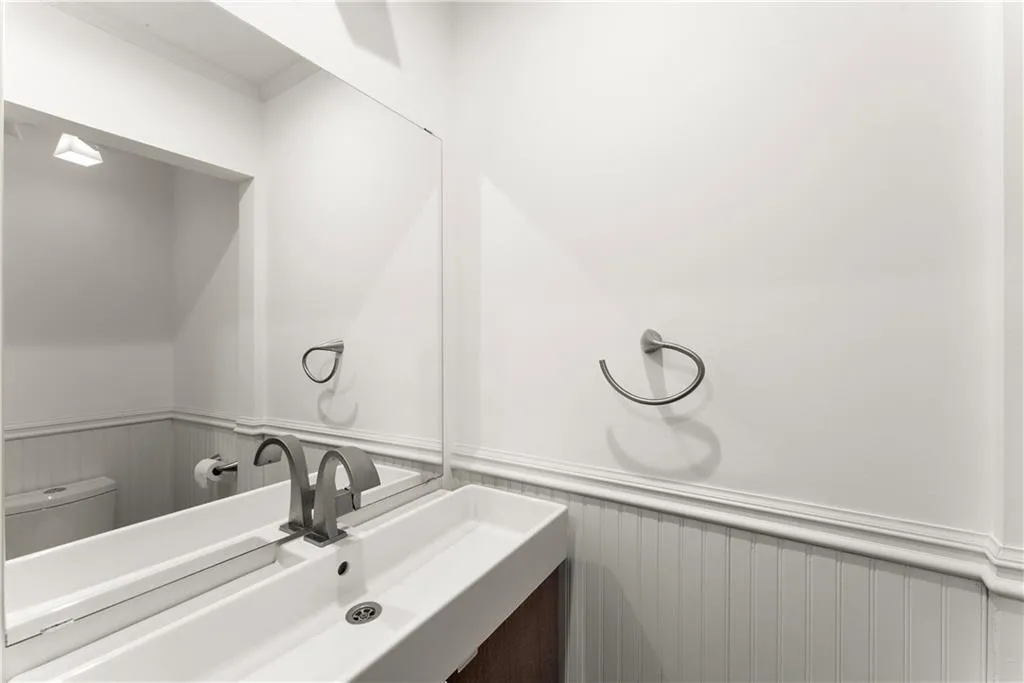 Bathroom featuring wainscoting, a decorative wall, vanity, and ornamental molding