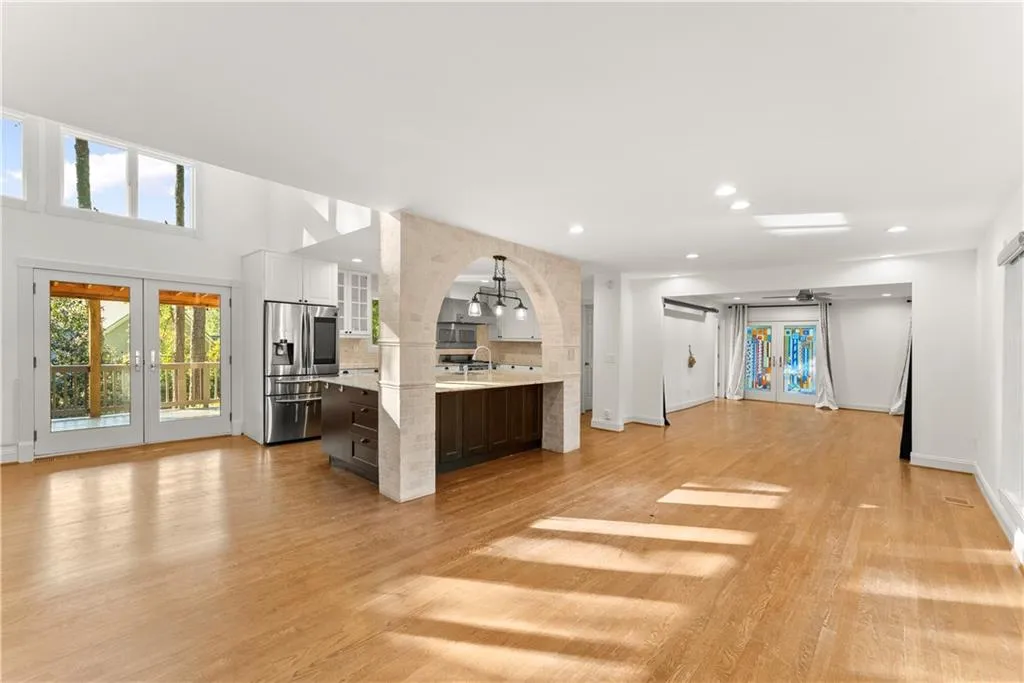 Unfurnished living room with french doors, light wood-style floors, recessed lighting, and arched walkways