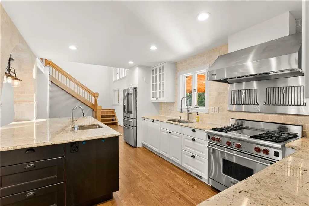Kitchen with light stone counters, appliances with stainless steel finishes, white cabinets, and recessed lighting