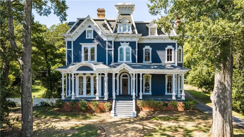 Victorian-style exterior with a deep blue facade, white trim, and a prominent front porch with decorative columns