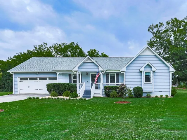 Light blue siding exterior with a white trim, front porch, and an attached two-car garage